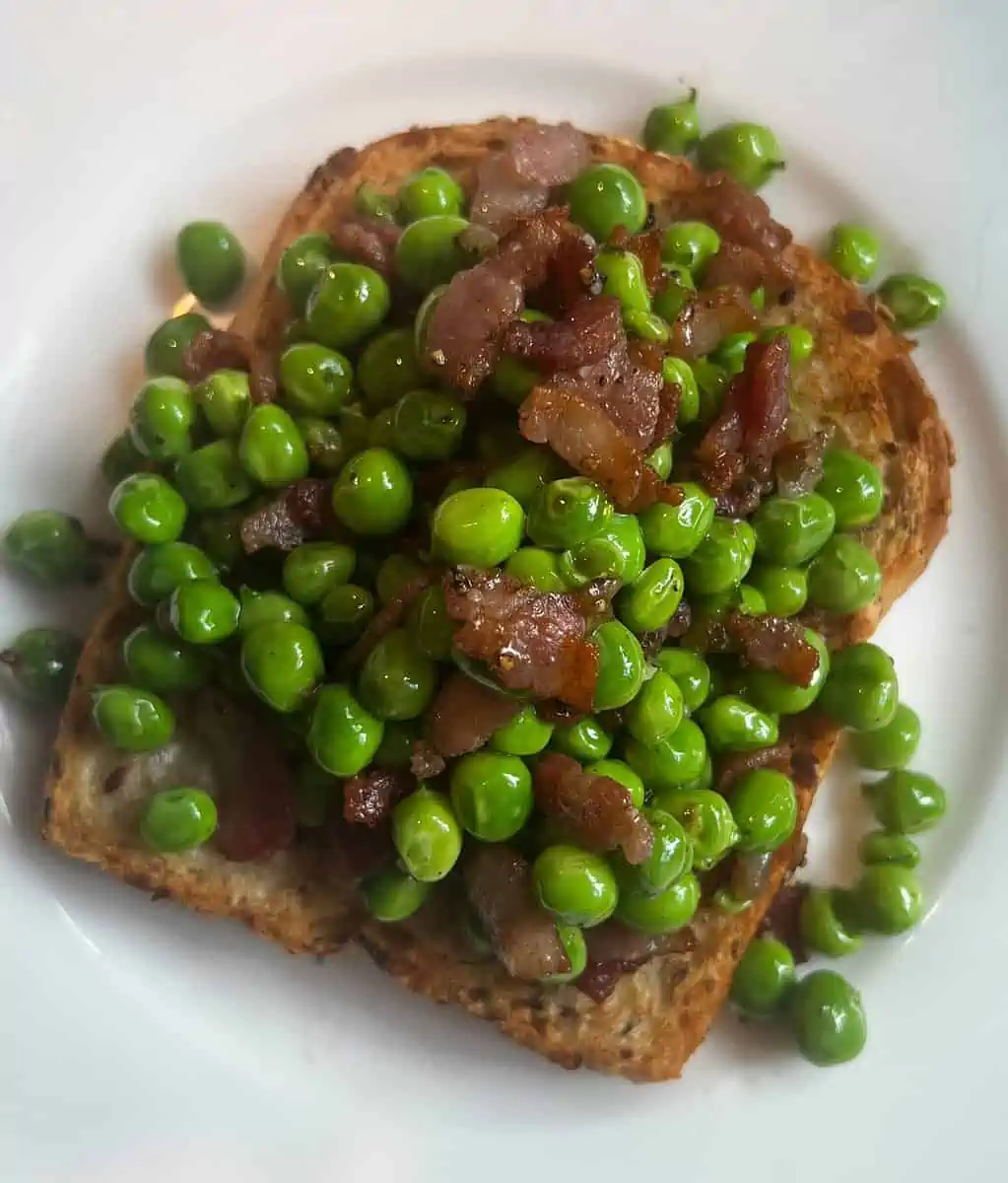 shelled peas and cooked bacon on toasted bread