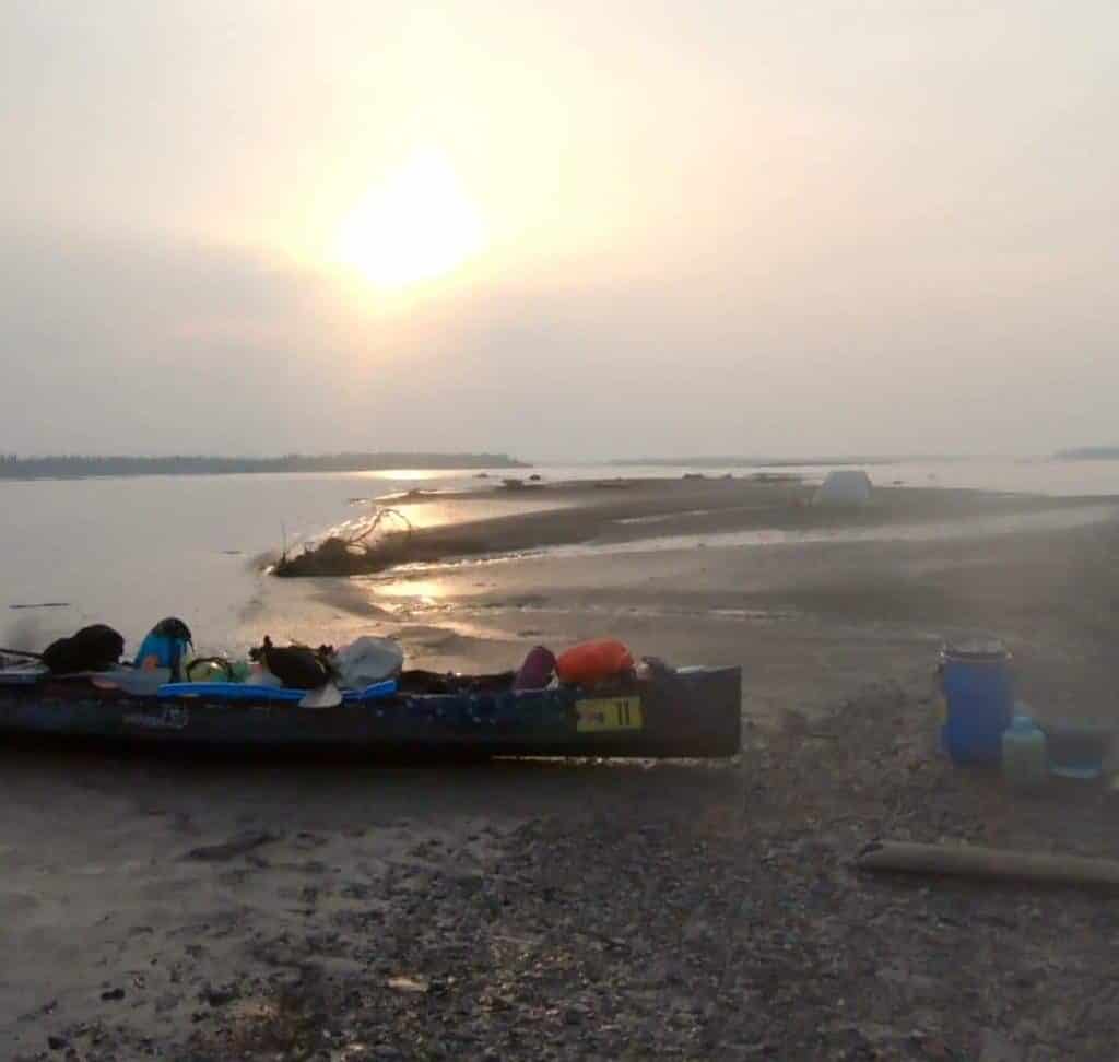 A racing canoe pulled ashore at a camp site