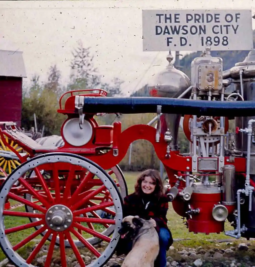 A woman and a dog posing with antique farm equipment