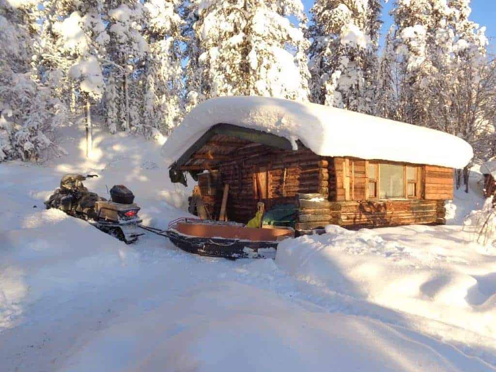 A snowmobile outside a log cabin in winter