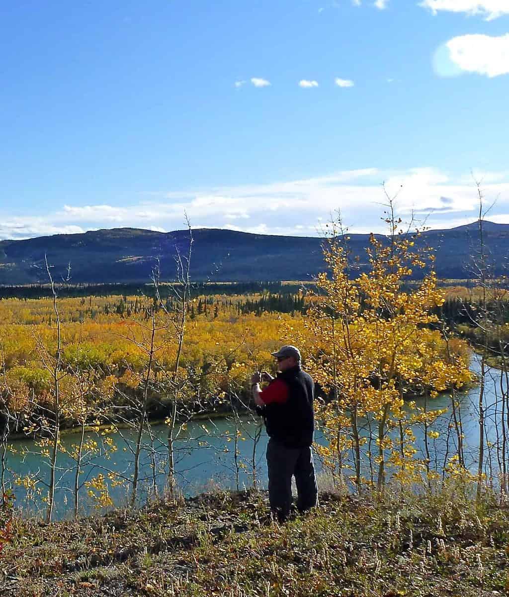 A man using binoculars to look at distant fall colours