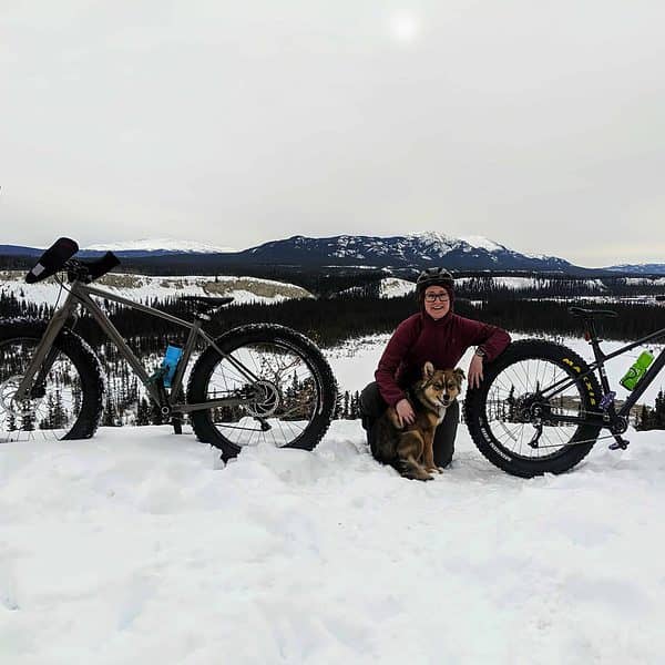 A woman with a dog and a mountain bike in winter