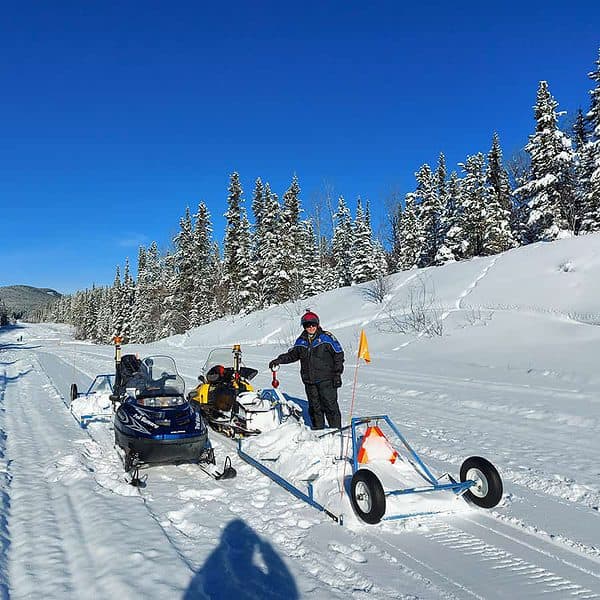 A man with a snowmobile and trail groomer