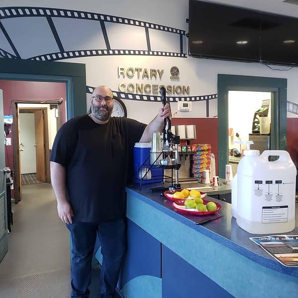 A man in a theatre lobby with a lemonade press