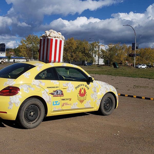 A yellow VW Beetle with popcorn sinage