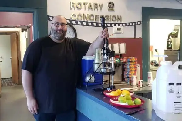 A man in a theatre lobby with a lemonade press
