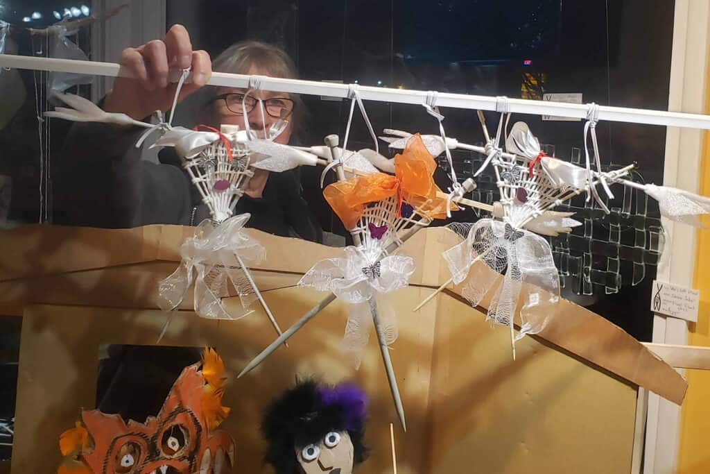 A woman setting up her puppets in a window