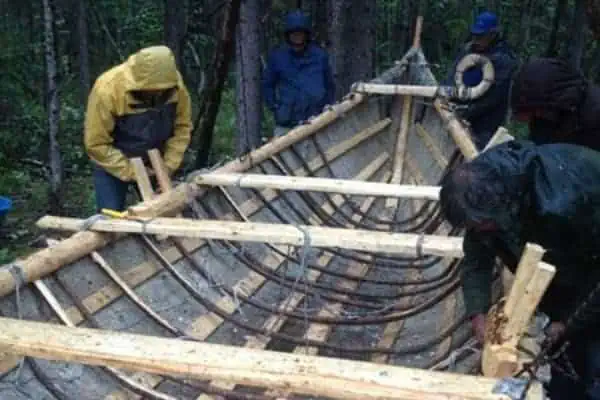 Dene men constructing a traditional moose skin boat